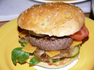 Cheeseburger mit selbst gebackenem Brötchen. SO muß das aussehen! (150 g frisch gewolftes Bio-Rind, belegt mit Feldsalat, frischen Röstzwiebeln, Cheddar, Tomaten, Gurken, Essiggurken, Ketchup, Senf und frisch aufgeschlagener Aioli)